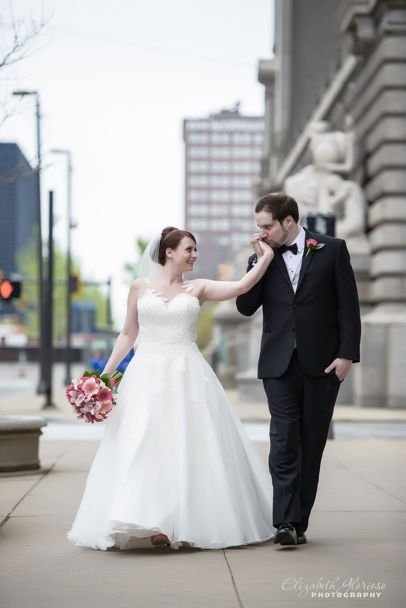 Photo of groom kissing bride\'s hand outside of the Cleveland Public Library